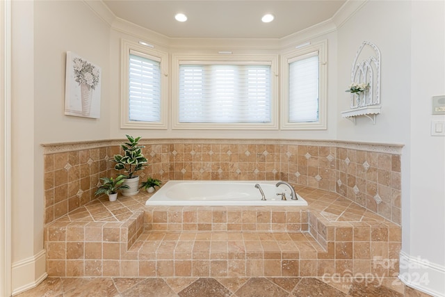 bathroom with crown molding and a relaxing tiled tub