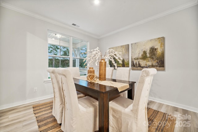 dining space with hardwood / wood-style floors and crown molding