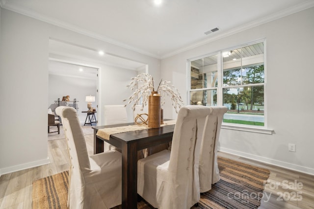 dining room with light hardwood / wood-style floors and crown molding