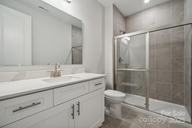 bathroom featuring vanity, toilet, a shower with door, and tile patterned flooring