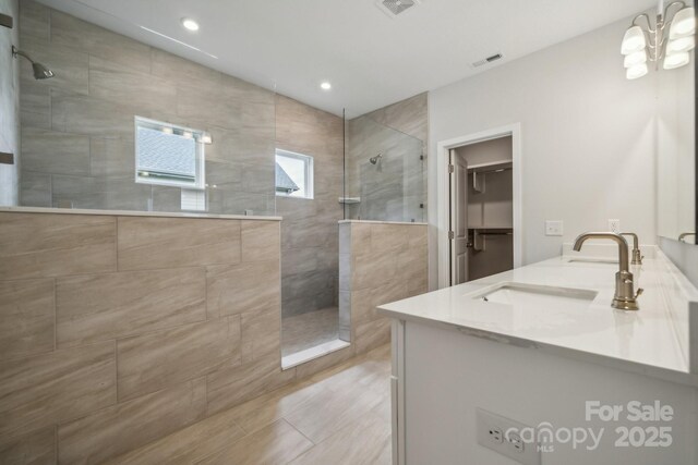 bathroom featuring tiled shower, vanity, and a chandelier