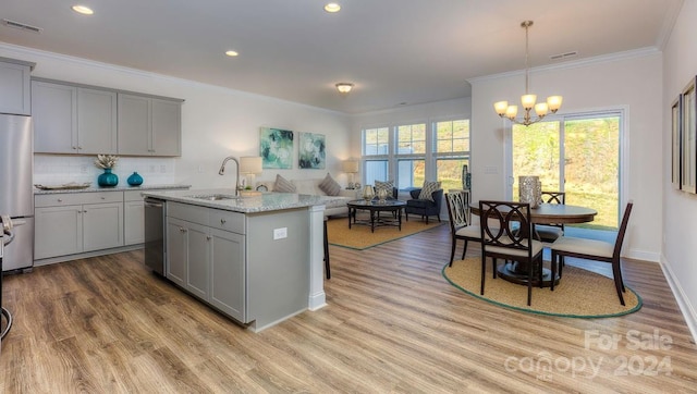 kitchen featuring gray cabinets, light stone countertops, a kitchen island with sink, and appliances with stainless steel finishes