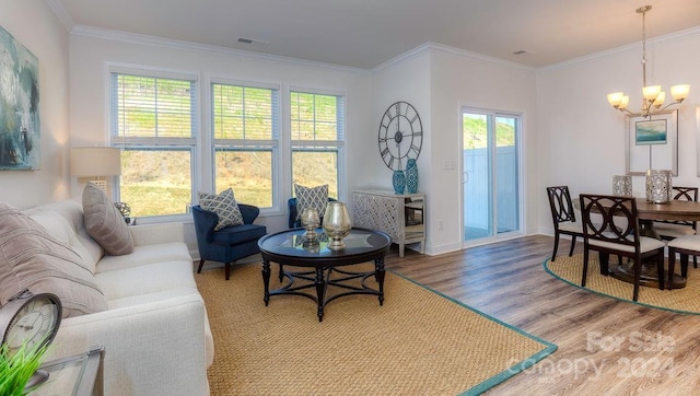 living room with hardwood / wood-style flooring, a notable chandelier, plenty of natural light, and ornamental molding