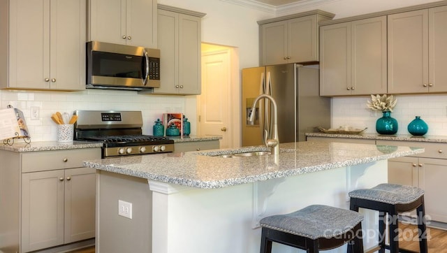 kitchen with a kitchen breakfast bar, decorative backsplash, light stone counters, and stainless steel appliances