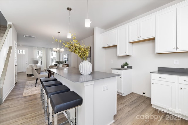 kitchen featuring pendant lighting, light hardwood / wood-style flooring, a kitchen island, and white cabinets