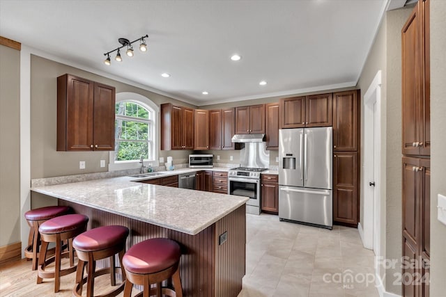 kitchen featuring a kitchen breakfast bar, stainless steel appliances, kitchen peninsula, and sink