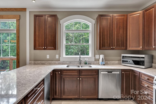 kitchen with light stone counters, sink, a wealth of natural light, and appliances with stainless steel finishes