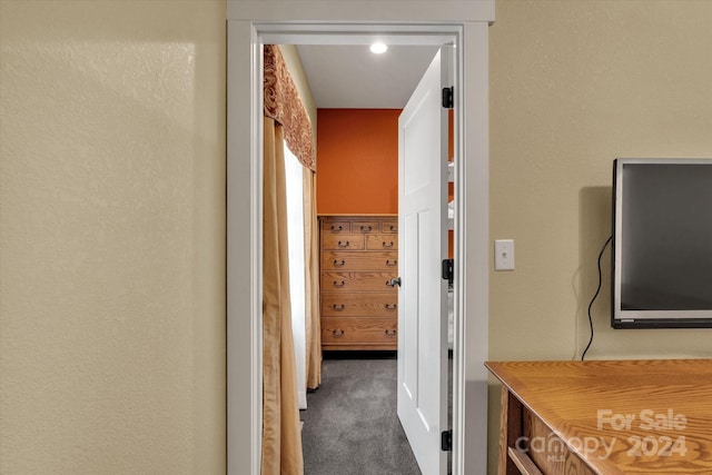 hall with dark colored carpet