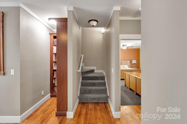 stairway featuring ceiling fan, crown molding, and hardwood / wood-style flooring