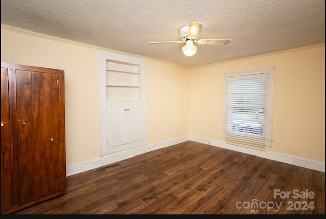 spare room featuring built in features, a textured ceiling, dark hardwood / wood-style floors, and ceiling fan