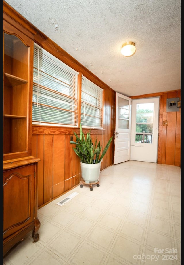 doorway featuring wooden walls and a textured ceiling