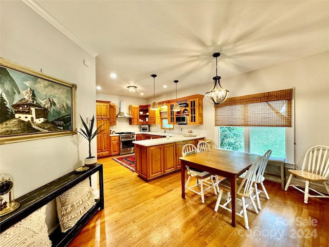 dining space with light hardwood / wood-style floors, ornamental molding, and an inviting chandelier