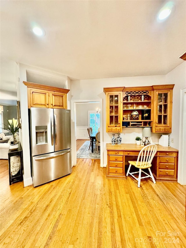 kitchen featuring stainless steel refrigerator with ice dispenser, light hardwood / wood-style floors, and built in desk