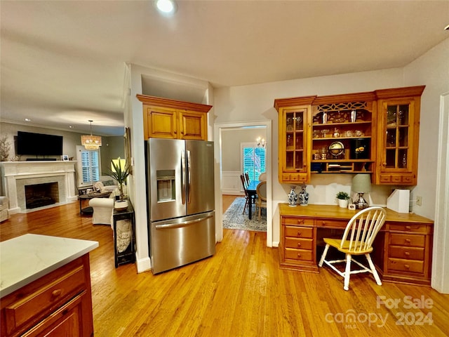 kitchen with built in desk, stainless steel refrigerator with ice dispenser, and light hardwood / wood-style flooring