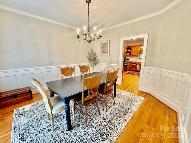 dining area featuring light hardwood / wood-style floors, crown molding, and a chandelier