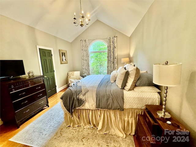 bedroom with lofted ceiling, a chandelier, and light wood-type flooring