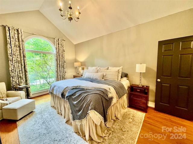 bedroom featuring vaulted ceiling, hardwood / wood-style floors, and a notable chandelier