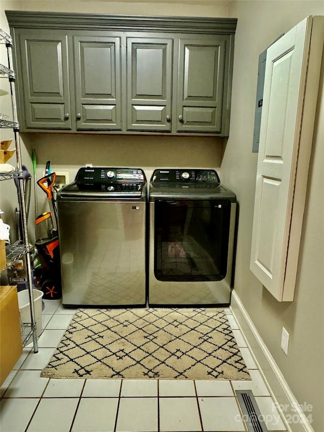 clothes washing area with washer and clothes dryer, light tile patterned floors, and cabinets