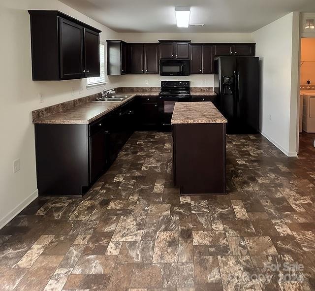 kitchen featuring black appliances, a center island, and sink