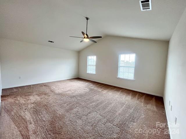 unfurnished room featuring lofted ceiling, ceiling fan, and carpet flooring