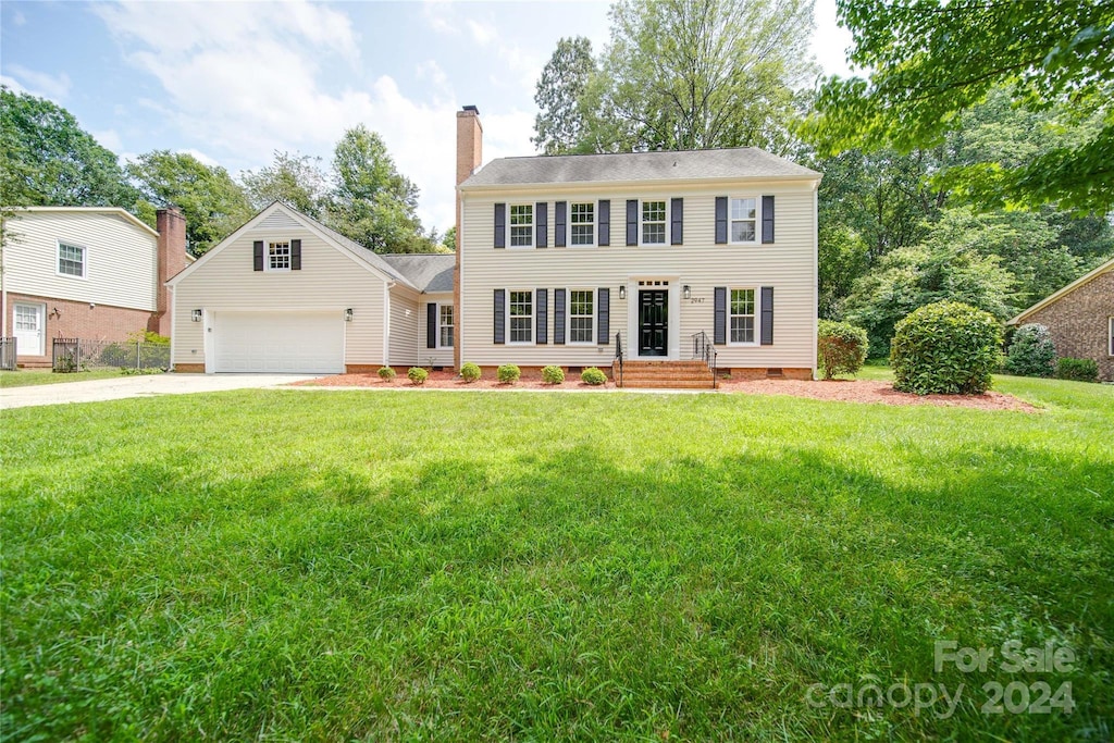 colonial home featuring a front lawn and a garage