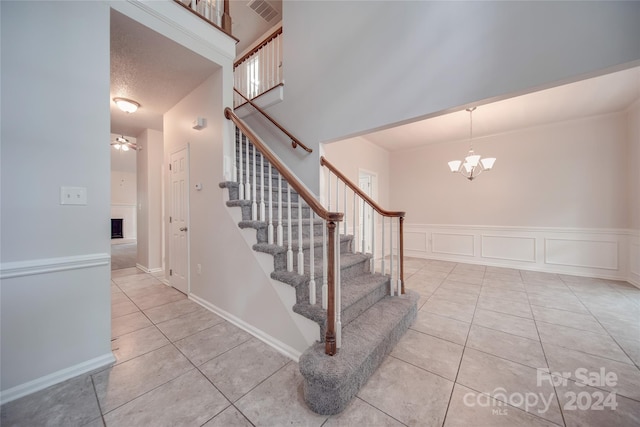 staircase with tile patterned flooring and a notable chandelier