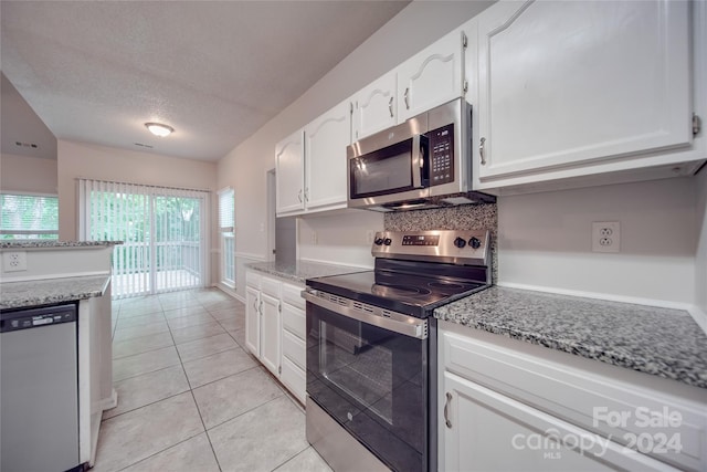 kitchen with light tile patterned floors, appliances with stainless steel finishes, and white cabinetry