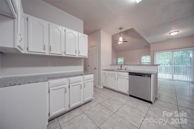 kitchen featuring vaulted ceiling, stainless steel dishwasher, sink, light tile patterned floors, and white cabinets