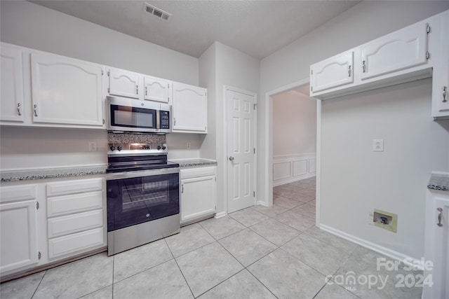 kitchen featuring light tile patterned flooring, stainless steel appliances, and white cabinetry