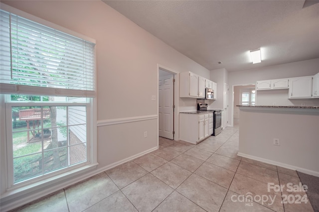 kitchen featuring light tile patterned floors, appliances with stainless steel finishes, plenty of natural light, and white cabinetry