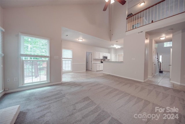 unfurnished living room with plenty of natural light, light carpet, and a towering ceiling