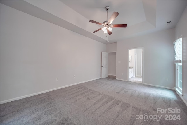 carpeted empty room featuring a raised ceiling and ceiling fan