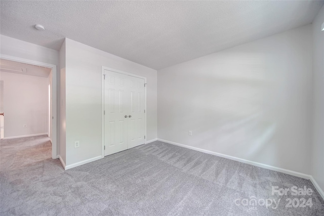 unfurnished bedroom with light colored carpet, a textured ceiling, and a closet