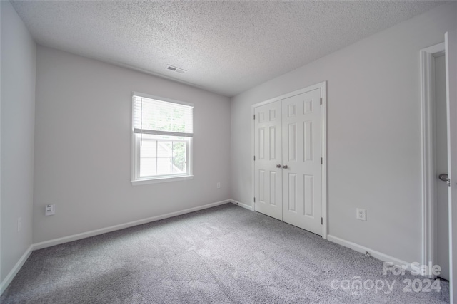 unfurnished bedroom with a textured ceiling, a closet, and carpet flooring