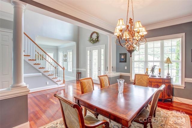 dining room featuring decorative columns, hardwood / wood-style floors, ornamental molding, and an inviting chandelier