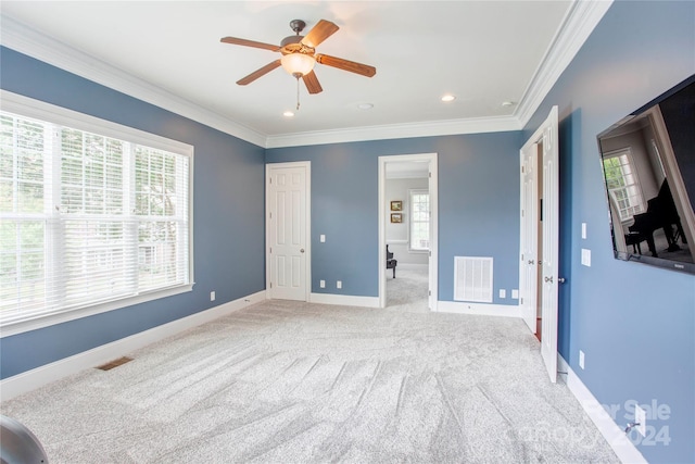 unfurnished bedroom featuring ceiling fan, light colored carpet, and crown molding