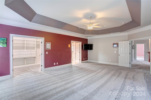 carpeted spare room featuring ceiling fan, a raised ceiling, built in features, and crown molding