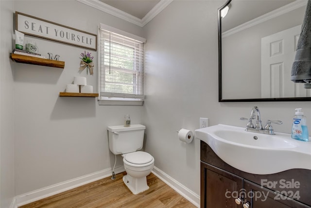 bathroom with wood-type flooring, vanity, toilet, and ornamental molding