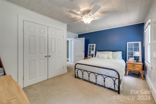 bedroom with ceiling fan, light colored carpet, multiple windows, and a closet