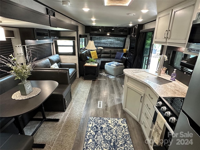 kitchen featuring light stone countertops, sink, dark wood-type flooring, stainless steel range oven, and white cabinets