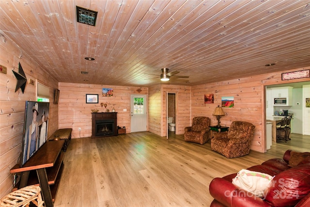 living room featuring wooden ceiling, light hardwood / wood-style floors, ceiling fan, and wooden walls