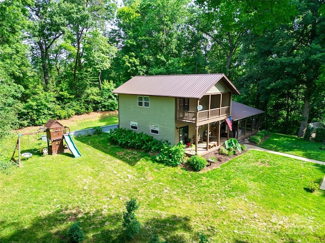 rear view of house featuring a playground, a sunroom, a lawn, and a patio