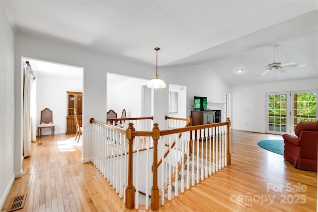 corridor with lofted ceiling, visible vents, an upstairs landing, baseboards, and light wood-style flooring