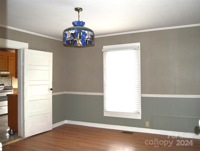 unfurnished dining area with dark hardwood / wood-style floors, crown molding, and an inviting chandelier