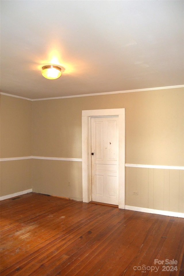 unfurnished room featuring crown molding and dark wood-type flooring