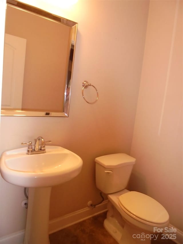 bathroom with a sink, toilet, and baseboards