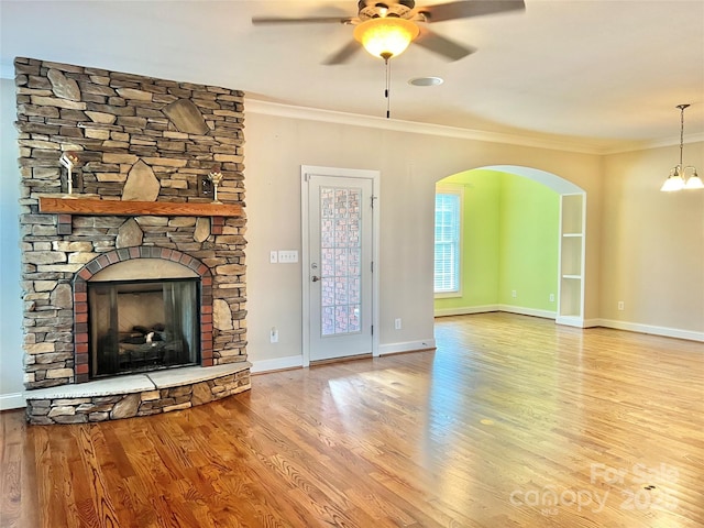 unfurnished living room with light wood finished floors, a fireplace, ornamental molding, and a ceiling fan