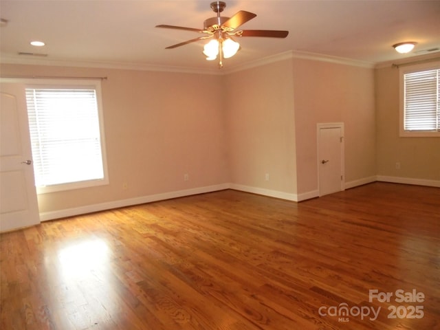 spare room with a wealth of natural light, baseboards, crown molding, and wood finished floors