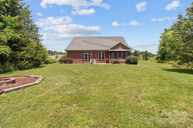 rear view of house featuring brick siding, a lawn, and a sunroom