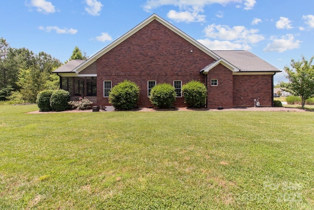 view of side of property with a yard, brick siding, crawl space, and a sunroom